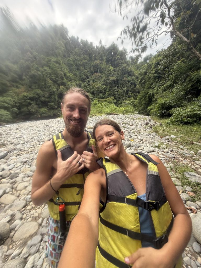 Couple in life jackets crossing river during Sumatra orangutan trekking