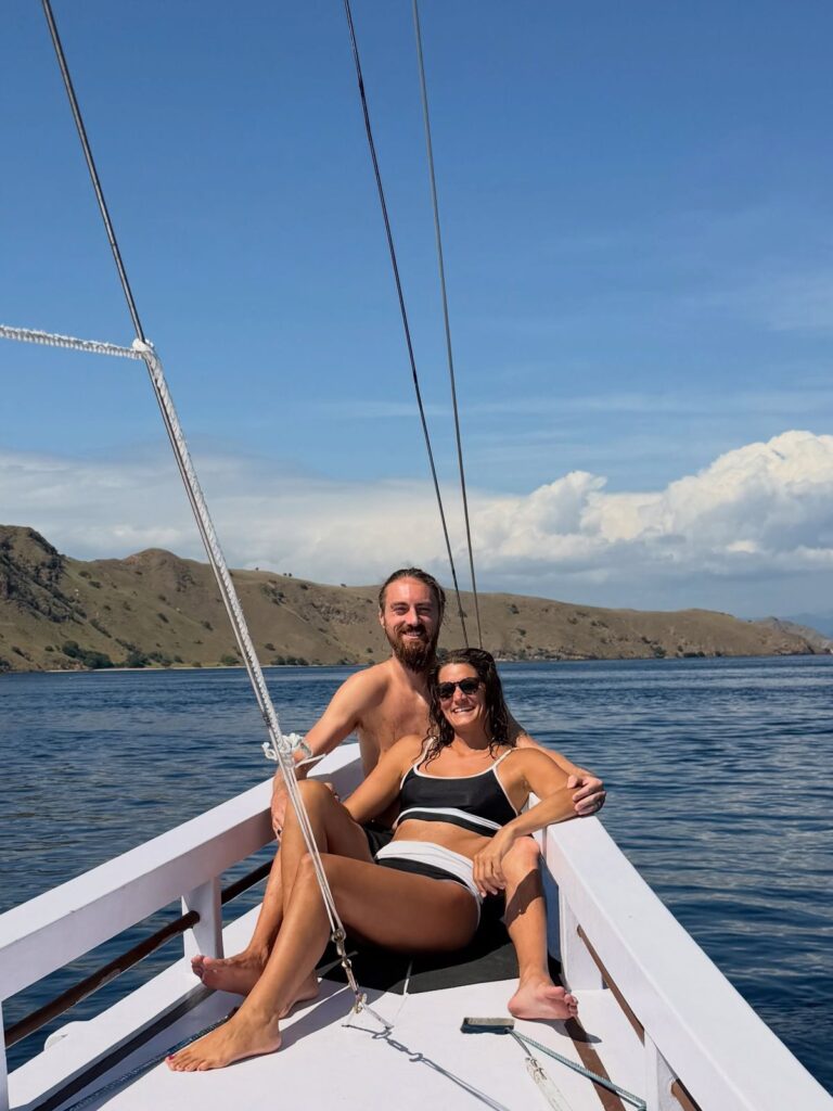Couple relaxing on the bow of a Komodo liveaboard boat between islands