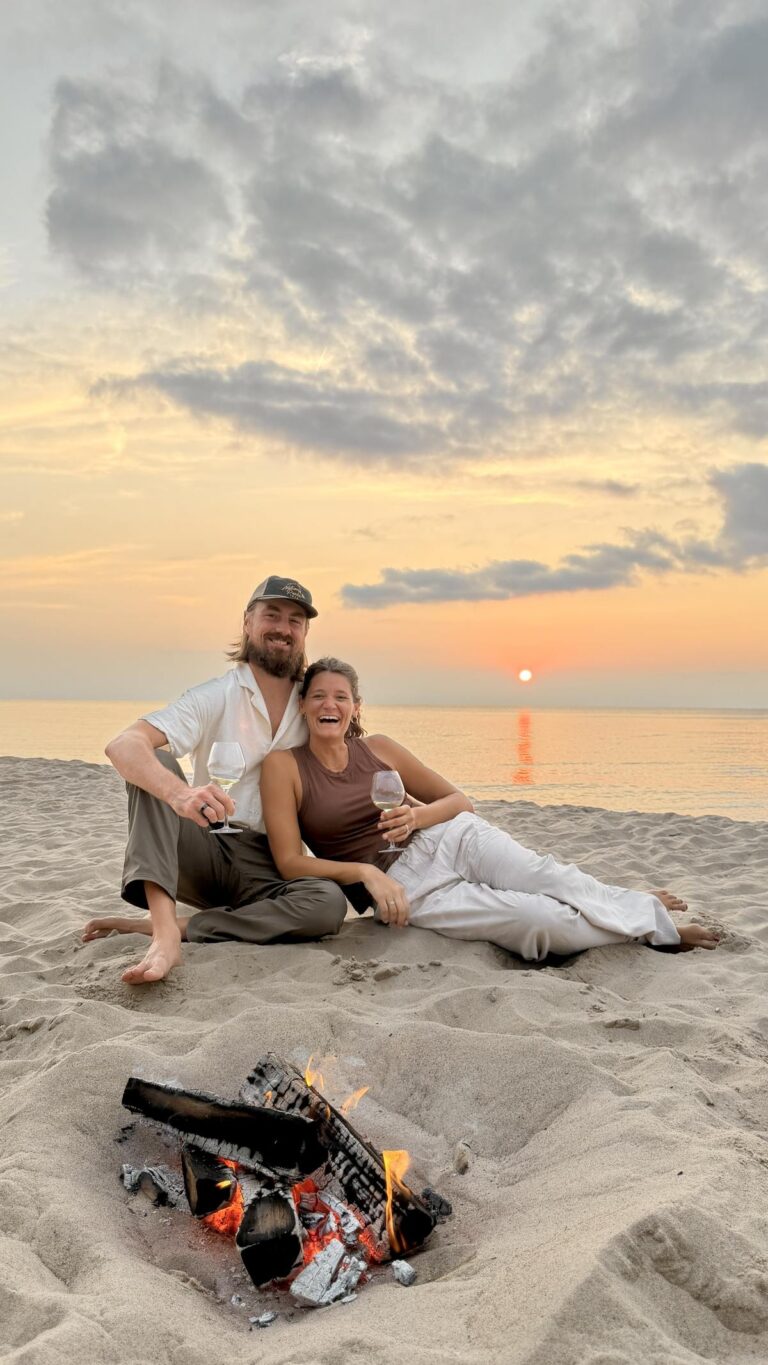 Couple drinking wine by a bonfire on the beach at sunset near New Buffalo, Michigan