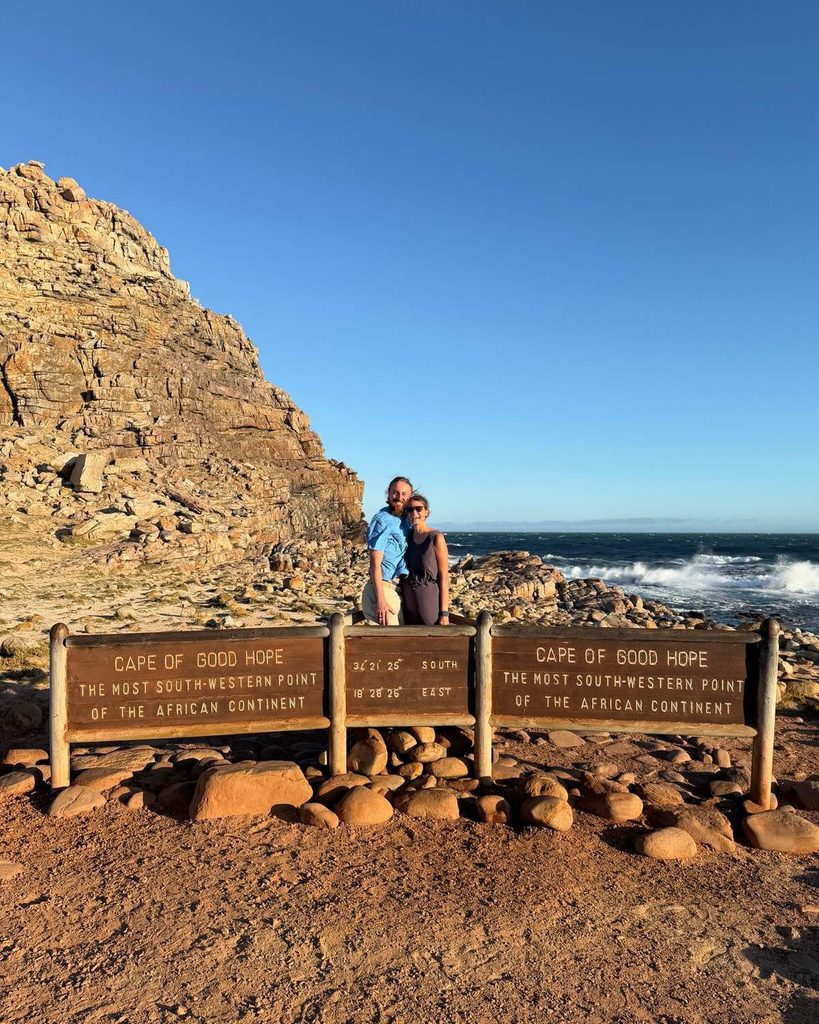 Couple posing at the Cape of Good Hope sign marking the most south-western point of the African continent