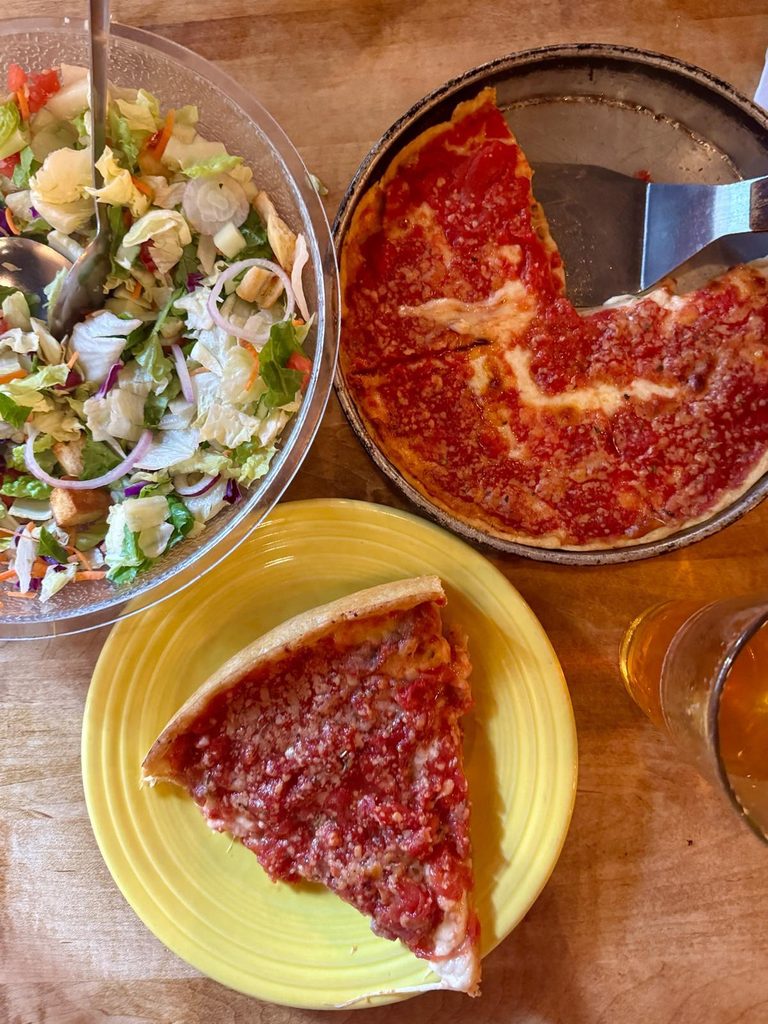 Slice of Lou Malnati's Chicago deep dish pizza with a side salad