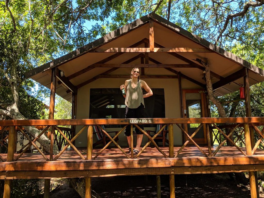 Woman smiling on the deck of a tented safari chalet at a lodge near Kruger National Park